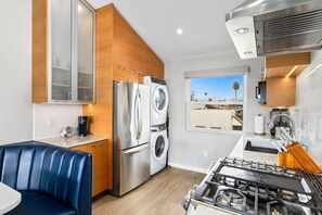 Une cuisine compacte équipée d’un lave-linge et d’un sèche-linge intégrés, d’une cuisinière à gaz et d’un coin repas avec une banquette bleue.