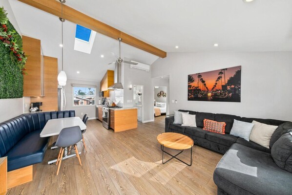 A modern apartment with a living room, dining area, kitchen, and a balcony.