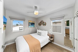 A bedroom with a bed, a ceiling fan, a nightstand, and a window.