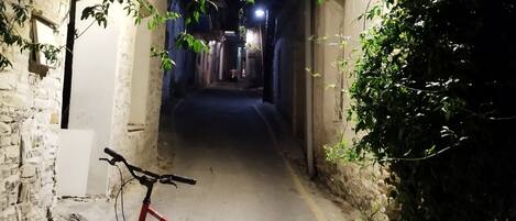 A narrow alleyway with a red electric scooter parked on the left.