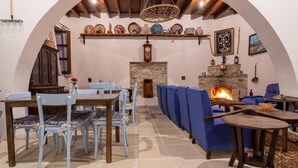 A cozy interior with a stone fireplace, blue furniture, and a rustic wooden ceiling. - Lazaros Stonehouse (Pano Lefkara)