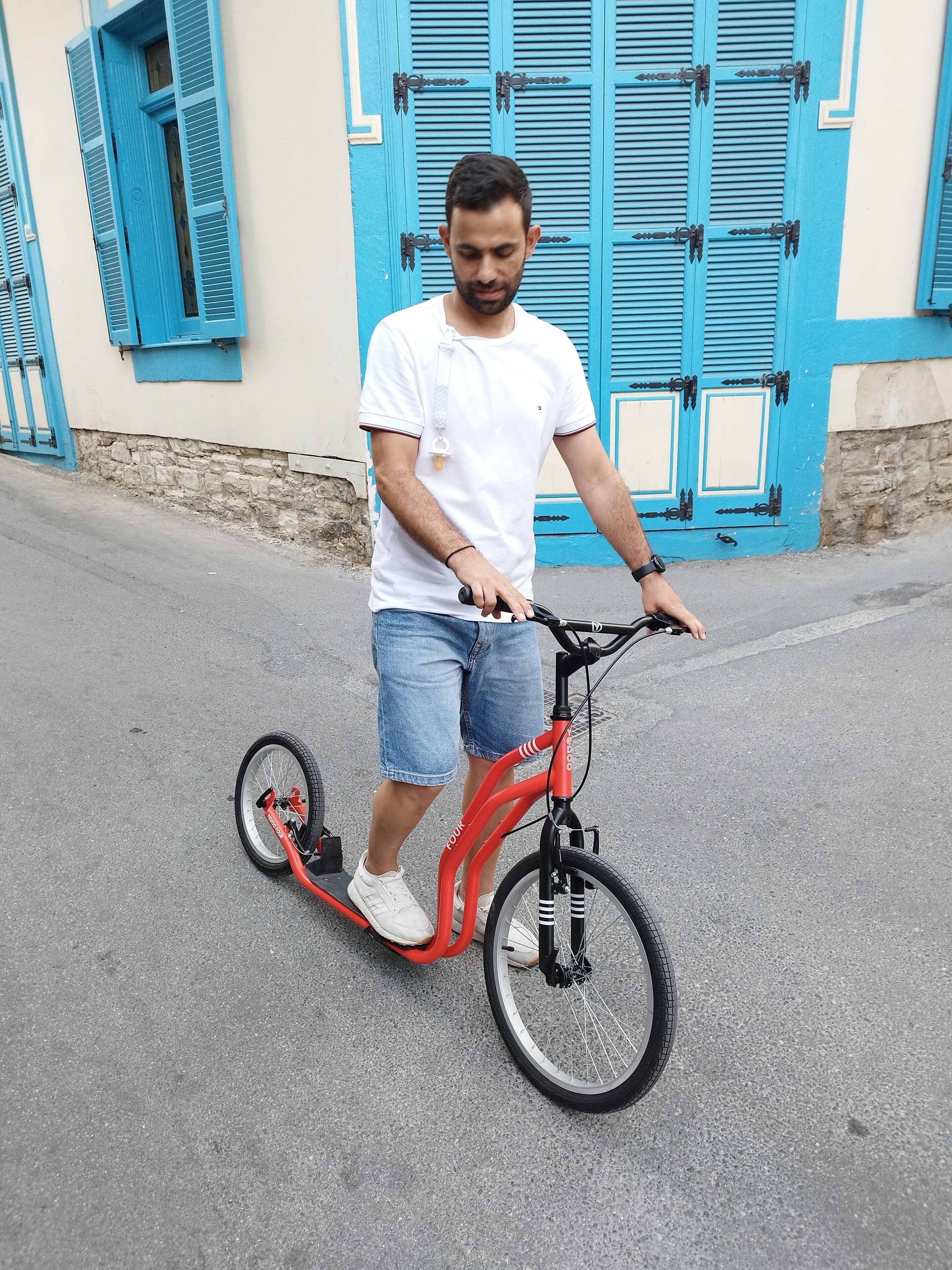 Una persona circulando en una patineta eléctrica roja por una carretera pavimentada.
