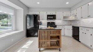 Une cuisine moderne avec des meubles blancs, un réfrigérateur en acier inoxydable, un four à micro-ondes et un lave-vaisselle.