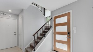 Un intérieur moderne avec un escalier en colimaçon, une porte en bois et un mur blanc.