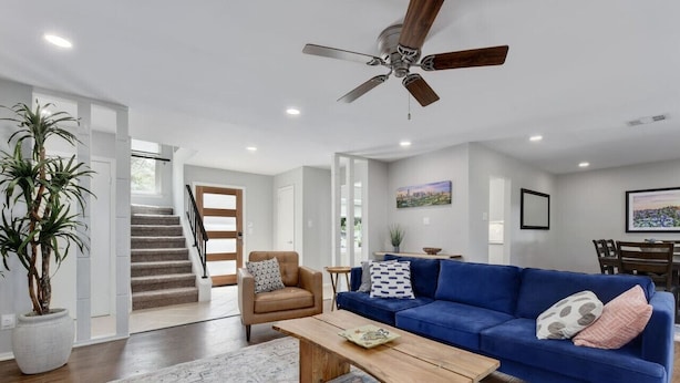 Un salon moderne avec un canapé bleu, une table basse en bois et un ventilateur de plafond.