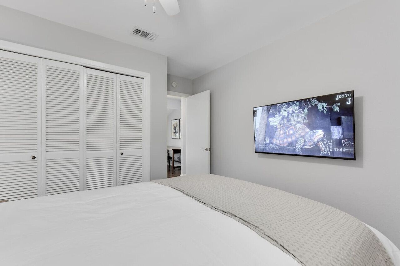 Een slaapkamer met een bed, een televisie aan de muur en een kast.