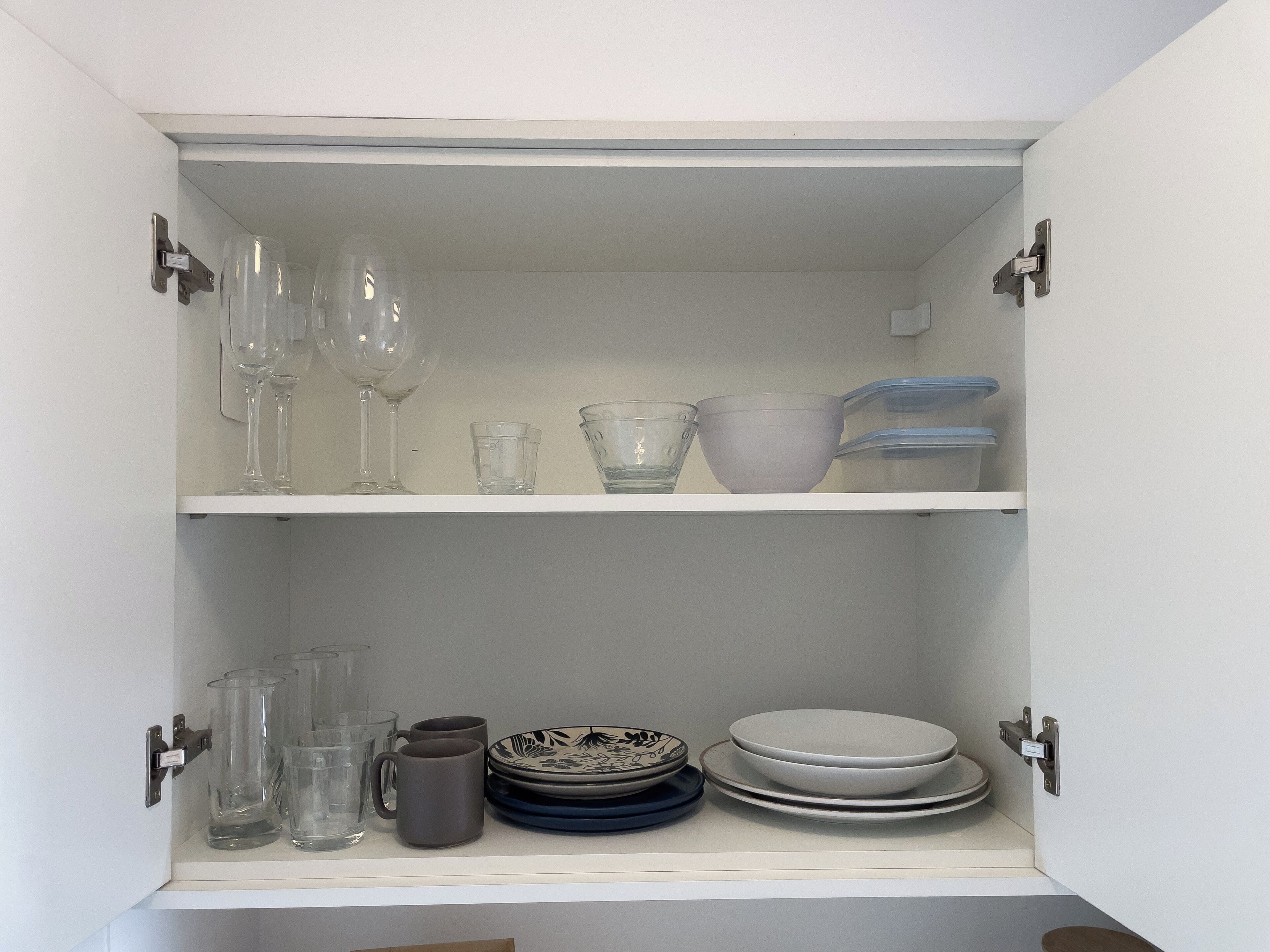 A cabinet with shelves containing various glassware and dishes.