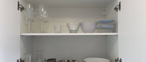 A cabinet with shelves containing various glassware and dishes.