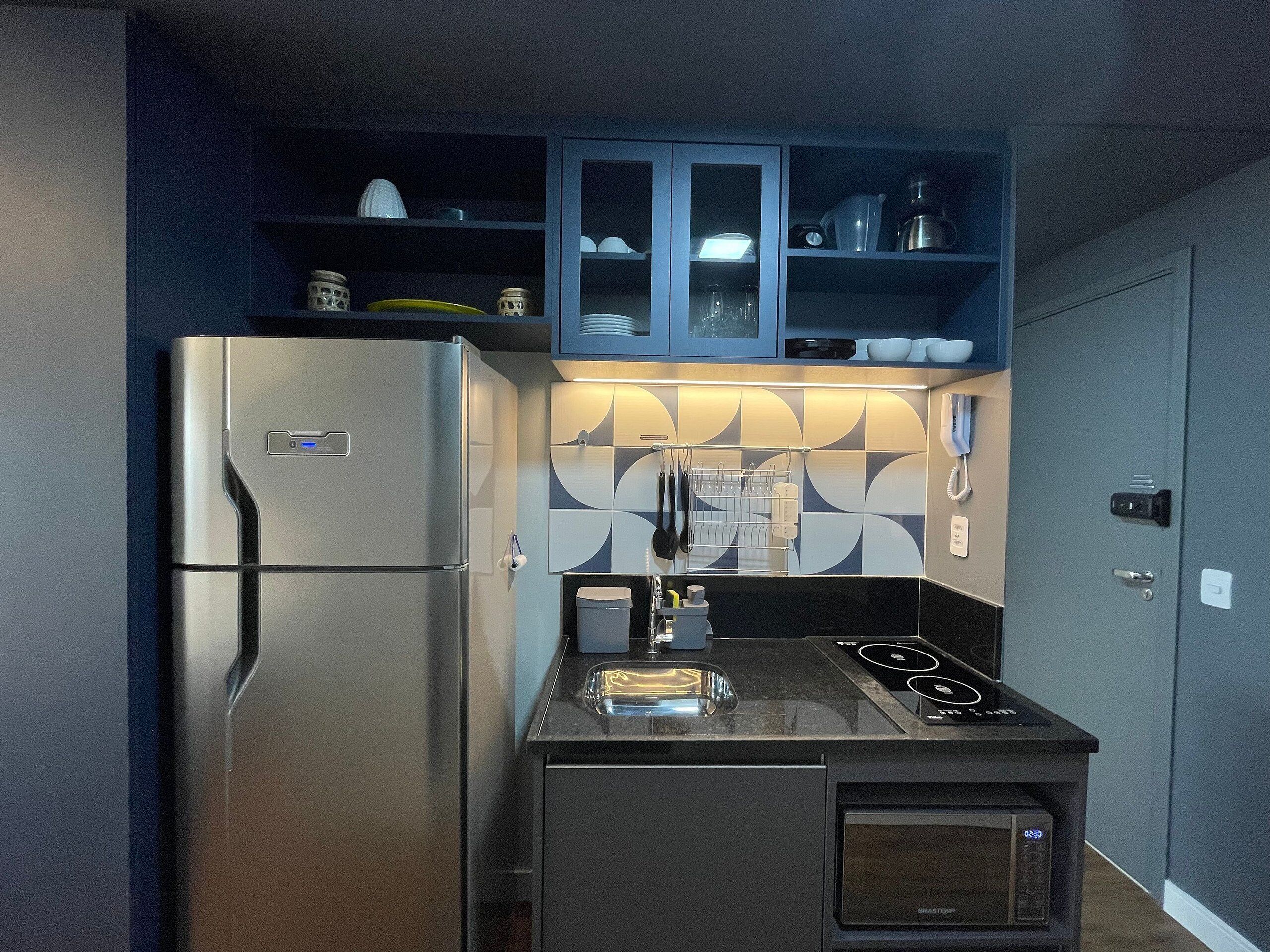Une cuisine compacte équipée d’un réfrigérateur, d’un four à micro-ondes et d’une cuisinière.