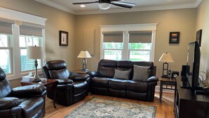 A living room with a leather sofa, a recliner, a coffee table, a TV, and a ceiling fan. - Recently updated Park Street Cottage with garage in Downtown Greeneville, TN. (Greeneville)