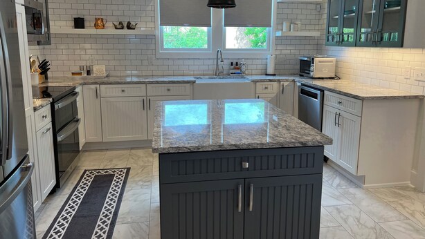 A modern kitchen with white cabinetry, a granite countertop, and a central island. - Recently updated Park Street Cottage with garage in Downtown Greeneville, TN. (Greeneville)