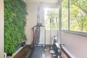 Une salle de sport à domicile équipée d’un tapis de course, de poids et d’un mur végétal.
