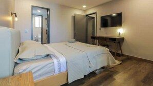Ett hotellrum med en säng, ett skrivbord, en tv och en spegel.