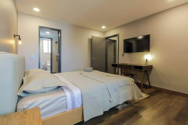 Une chambre d’hôtel avec un lit, un bureau, une télévision et un miroir.