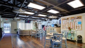 Een ruime lobby met een hoge plafond, houten vloer, een zithoek met een kerstboom en een prikbord met notities.