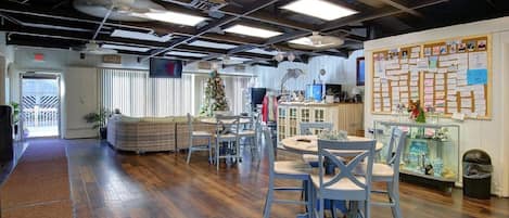 Un vestíbulo espacioso con techo alto, piso de madera, una zona de estar con un árbol de Navidad y un tablón de anuncios con notas.