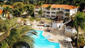 Un resort con piscina, palmeras y vistas a las montañas.