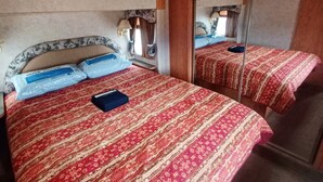A bedroom with a large bed, a bedside table, a lamp, and a mirror.