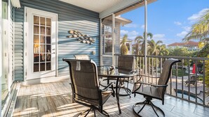 Une terrasse couverte avec une porte vitrée, des chaises en osier et une table.