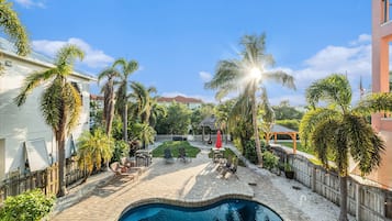 A swimming pool with a sunken center, surrounded by palm trees and a wooden deck.