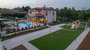 A modern house with a swimming pool, a covered patio, and a children's play area. - Lovely home in Kadumi (Kadumi)