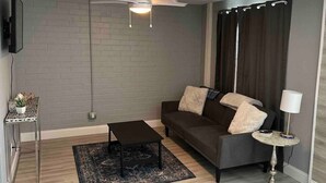 Una sala de estar con sofá, mesa de centro, televisor y ventilador de techo.