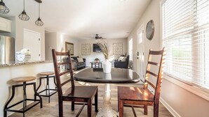 A dining area with a round table and four wooden chairs, a white vase with dried flowers, and a ceiling fan. - The Clemson Cottage - 3.6 mi. to Memorial Stadium (Seneca)