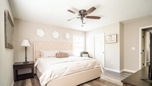 A bedroom with a bed, a nightstand, a ceiling fan, and a door. - The Clemson Cottage - 3.6 mi. to Memorial Stadium (Seneca)