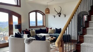 A spacious living room with a high ceiling, wooden floors, a large window, and a staircase. - HUGE VIEWS + LUX Finishes Outside Aspen (Basalt)