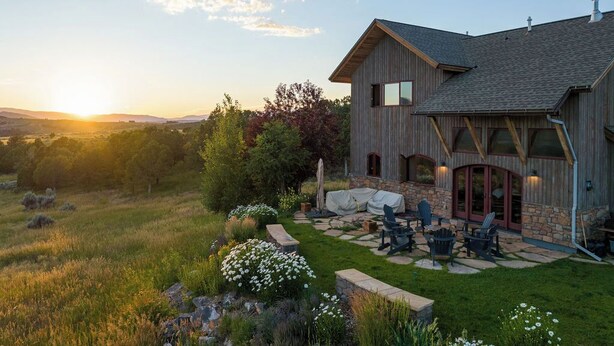 A two-story house with a stone foundation and wooden siding, featuring a patio with outdoor furniture and a stone pathway. - HUGE VIEWS + LUX Finishes Outside Aspen (Basalt)