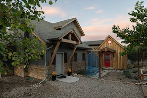 A rustic building with a stone foundation, a wooden exterior, and a red door.