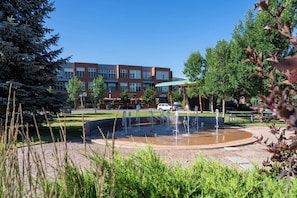 A courtyard with a fountain, surrounded by trees and a building with multiple windows.