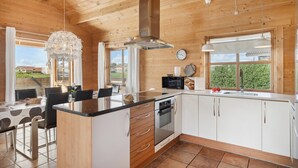 A modern kitchen with wooden cabinets, a central island, and a dining area with a table and chairs. - Stunning home in Vinderup with kitchen (Vinderup)
