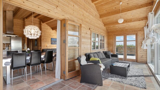 A wooden cabin interior with a dining area, a sofa, and a view of the outdoors. - Stunning home in Vinderup with kitchen (Vinderup)