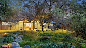A rustic cabin with a wooden exterior, surrounded by a natural landscape with rocks and vegetation.