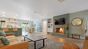 A spacious living room with a fireplace, a dining area, and a kitchen.