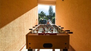 A foosball table in a narrow corridor with a view of trees and a building outside. - Baglio Cuttaia - Apartment for families. (Carini)