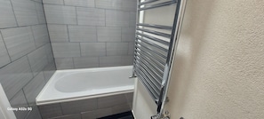 A bathroom with a bathtub, tiled walls, and a towel rack. - Coventry 1bed Apartment -privategarden-freeparking (Coventry)