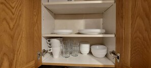 A kitchen cabinet with white plates, bowls, and clear drinking glasses. - Coventry 1bed Apartment -privategarden-freeparking (Coventry)