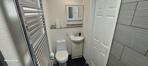 A compact bathroom with a toilet, sink, and mirror. - Coventry 1bed Apartment -privategarden-freeparking (Coventry)