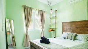 Ein Zimmer mit einem hölzernen Bett, einem Spiegel, einem Fenster mit Vorhängen und einer Pendelleuchte.