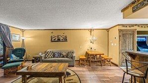 A cozy living room with a sofa, a coffee table, and a TV. - Those Who Wander Are Not Always Lost – Cozy Mountain Stream Condo with Fireplace (Gatlinburg)