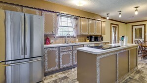 Una cocina con un refrigerador de acero inoxidable, un fregadero, una cafetera y un comedor con sillas.