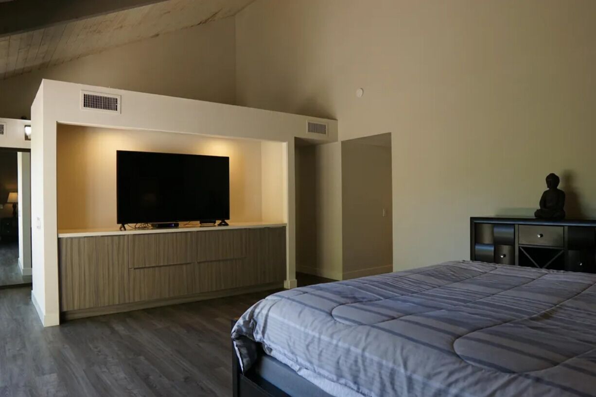 Une chambre moderne dotée d’un grand lit, d’un téléviseur intégré et d’un design minimaliste.