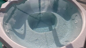 Ein Whirlpool mit transparenter Abdeckung, umrandet von Stein oder Beton.