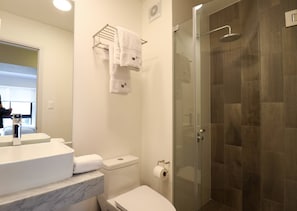A modern bathroom with a marble countertop, a glass shower enclosure, and a toilet with a paper towel dispenser. - Wynwood Residencial in Miraflores (Lima)