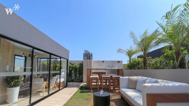 A modern outdoor patio with a sofa, chairs, and a table. - Wynwood Residencial in Miraflores (Lima)