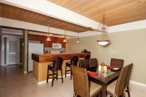 Une cuisine moderne avec des meubles en bois, un îlot central et des luminaires suspendus.