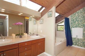 Une salle de bain avec un plafond en bois, deux lavabos, une baignoire et un rideau de douche.