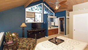 Ein Schlafzimmer mit einem Bett, einem Fernseher, einer Kommode und einem durch eine offene Tür einsehbaren Badezimmer.